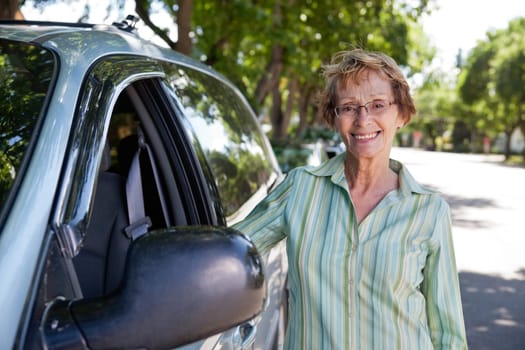Portrait of beautiful senior woman standing near car