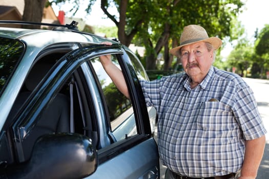 Portrait of senior man standing near car