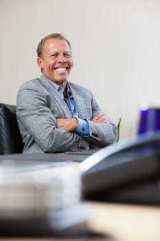 Portrait of smiling mature executive sitting with hands folded