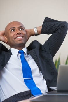 Relaxed Afro American business man sitting at his desk looking into the air