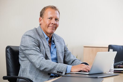 Portrait of smiling businessman working on laptop