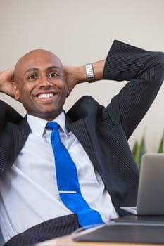 Executive leaning back in chair with hands on back of head