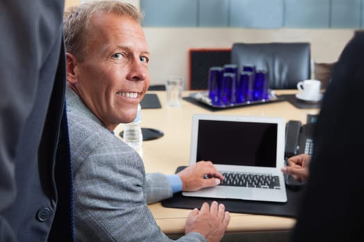 Portrait of mature man using laptop in office
