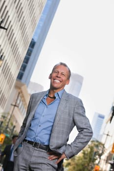 Smiling mature businessman standing with buildings in background