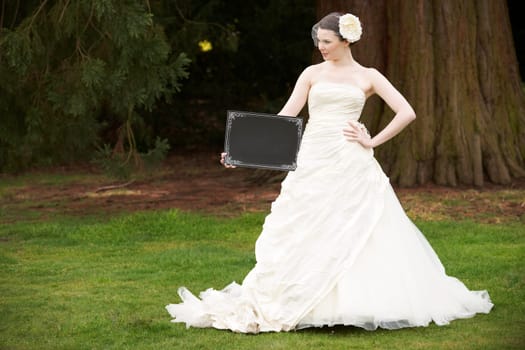 Pretty bride in wedding dress holding a blank board with space for copy