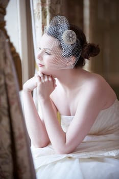 Pretty bride looking out of window and smiling on her wedding day