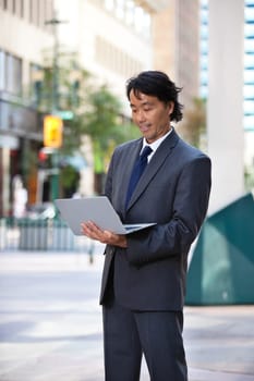 Businessman using laptop while standing on street