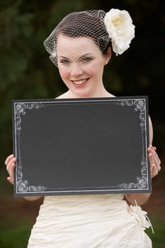 Pretty bride in wedding dress holding a blank board with space for copy