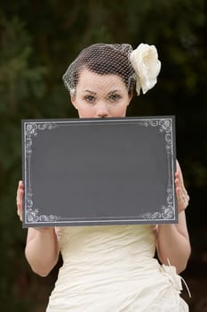 Pretty bride in wedding dress holding a blank board with space for copy