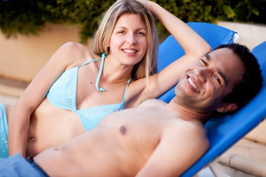 A happy couple on beach chairs, looking at the camera