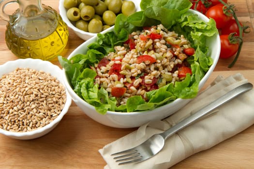 a dish with spelt salad with tomatoes,olive and salad