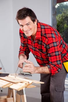 A man looking at the camera holding an electric sander