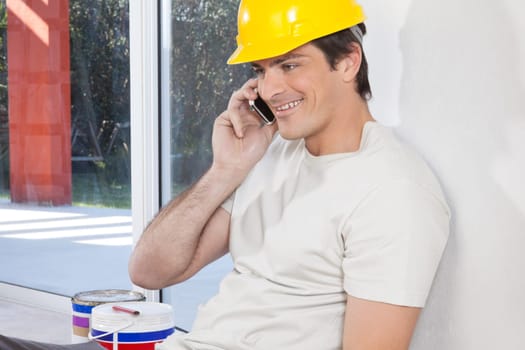Smiling man with hard hat having conversation on mobile phone