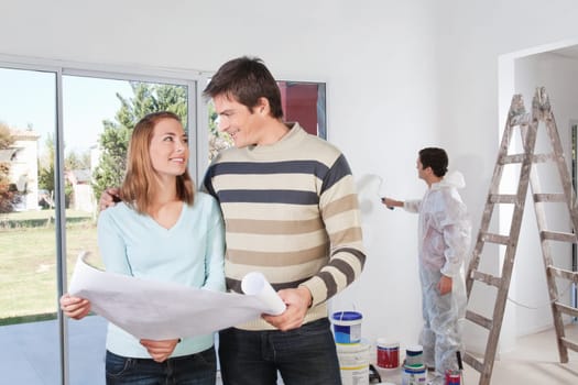 Young couple looking at each other with painter in background