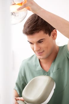 A young male dentist at work adjusting chair and light