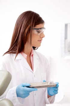 Dentist holding stainless steel tray of sterile tools