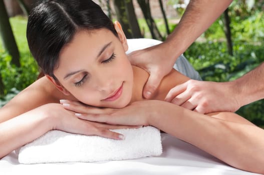 An attractive Caucasian woman getting massaged by a therapist