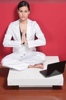 Young businesswoman doing yoga while sitting next to her computer