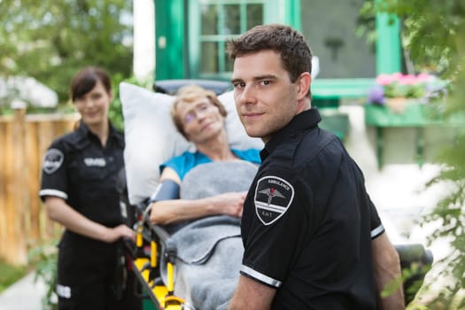 Serious ambulance worker with patient on stretcher