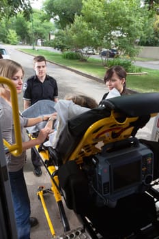 Senior woman being loaded onto ambulance in residential area