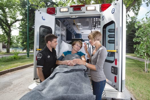 Senior woman looking at daughter / caregiver while entering ambulance