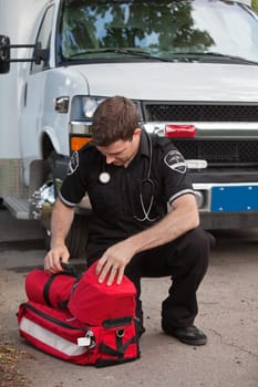 Male emergency medical services professional (EMS) with portable oxygen unit near ambulance
