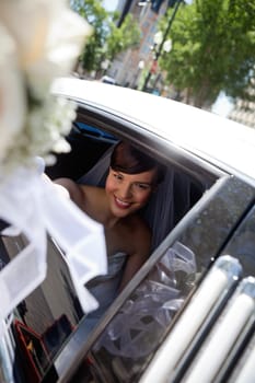 Happy bride looking at camera holding out wedding bouquet