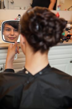 Bride looking in mirror at hair style before wedding