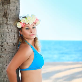 Beautiful woman near the trunk of palm tree