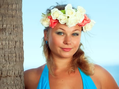 Woman is posing near the trunk of palmtree
