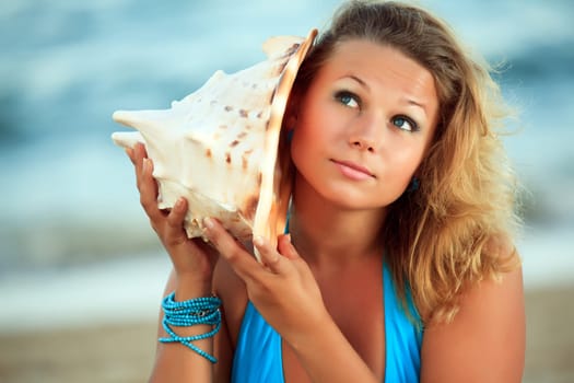 Young beautiful woman is listening seashell music