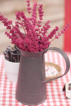 A stylish arrangement of lavender stands in a metal pitcher on a table.