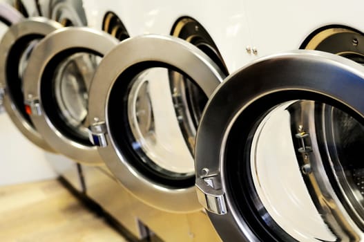 A row of industrial washing machines in a public laundromat