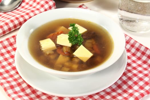a bowl of beef consommé with egg custard and parsley