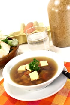 a bowl of beef consommé with egg custard and parsley