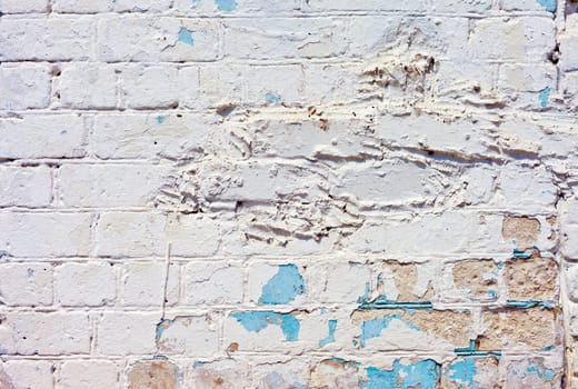 A white roughly textured brick wall painted with white paint