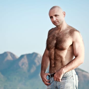 Muscular, handsome man in the background of  mountains