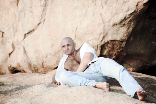 Handsome man lies on the rock outdoor