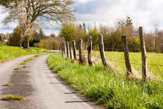 Countryside landscape in France with a small road and fence pasture