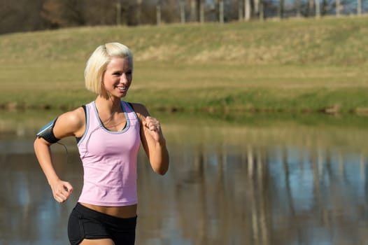 Young woman jogging recreational running by river sunny day