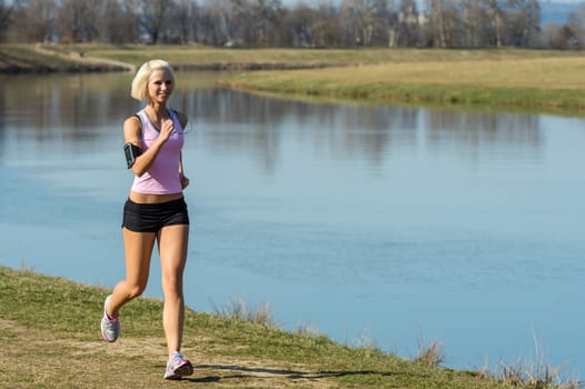 Young woman jogging recreational running by river sunny day