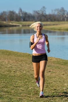 Young woman jogging recreational running by river sunny day