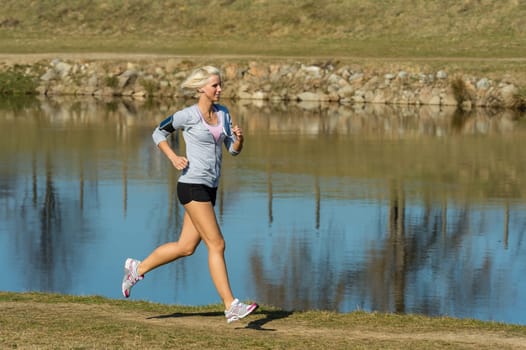 Running woman outdoor sport by river bank sunny day