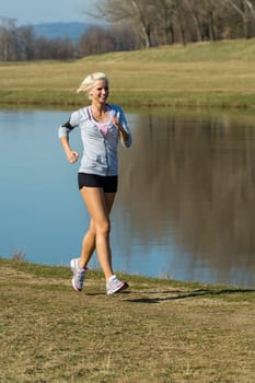 Running woman outdoor sport by river bank sunny day