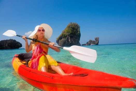 Beautiful young woman kayaking in tropical lagoon