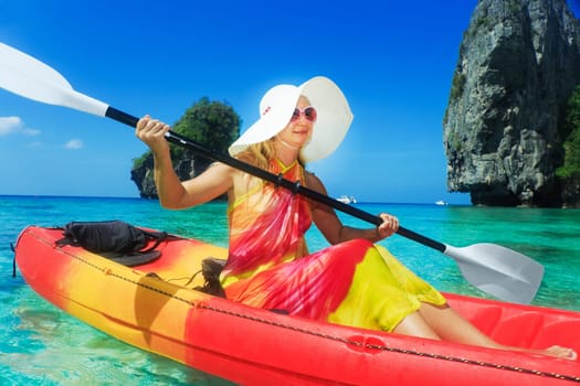 Beautiful young woman is kayaking in tropical lagoon
