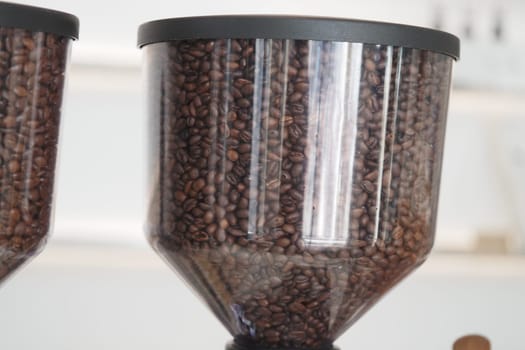 Dark roasted coffee beans fill clear containers in a cafe setting.