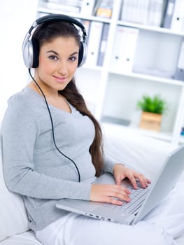 Young woman sitting on couch and working on laptop