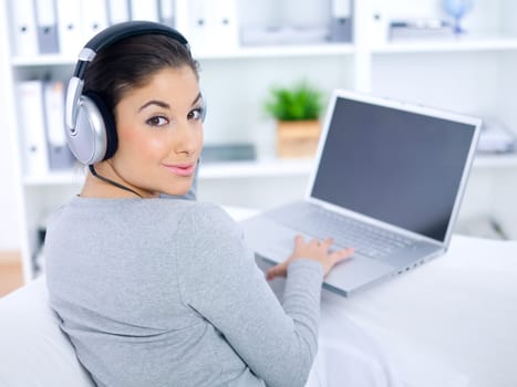 Young woman sitting on couch and working on laptop