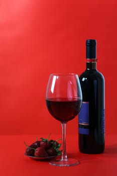 Red wine and glass with red background